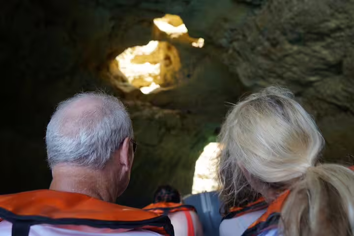 Tourists in life jackets explore Algarve's stunning sea caves on a private boat tour from Lisbon, highlighting natural beauty.