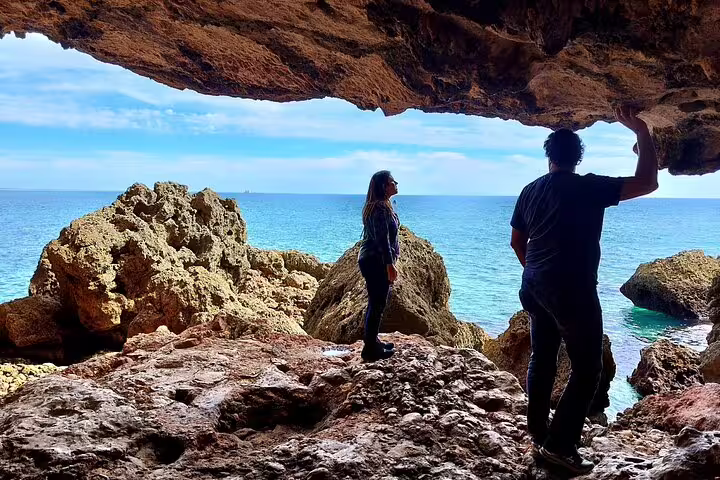 Explorers admire stunning coastal views from a rocky cave on a Private 4X4 Jeep & Beach Picnic Tour in Arrábida, Sesimbra-Lisbon.