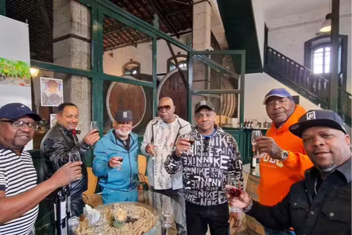 Group enjoying wine tasting in a traditional Arrabida cellar, part of a scenic tour from Lisbon highlighting Portuguese culture.
