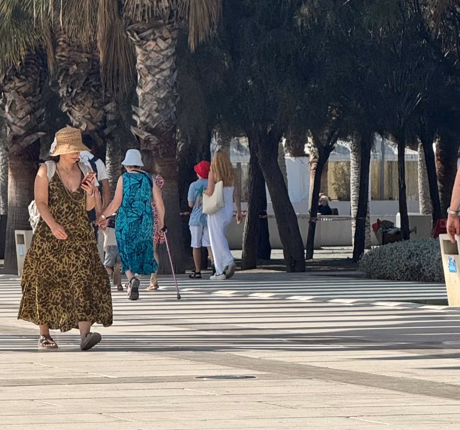 Travelers stroll under palm trees in Lisbon, following an audio guided City Quest scavenger hunt route