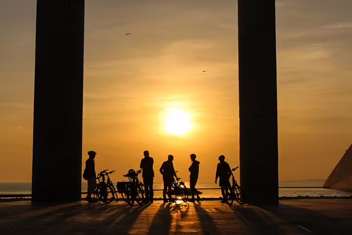 Silhouetted cyclists enjoy a sunset view during a private bike tour in Lisbon and Belem, capturing scenic urban beauty.