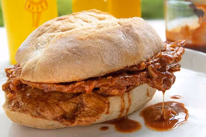 Traditional Lisbon bifana sandwich dripping with savory sauce, highlighting a must-try on the Ultimate Lisbon Food Tour.