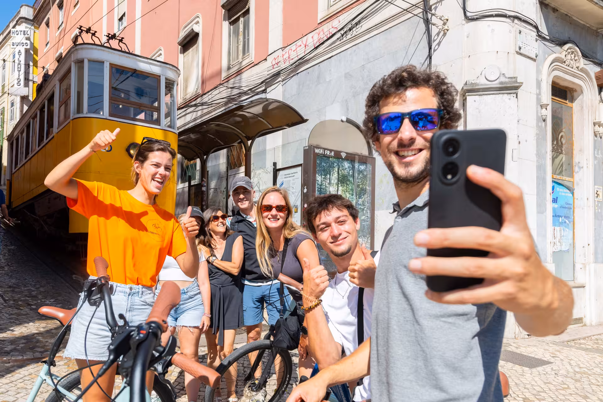 Happy group taking a selfie during a Lisbon bike tour near the famous yellow tram.
