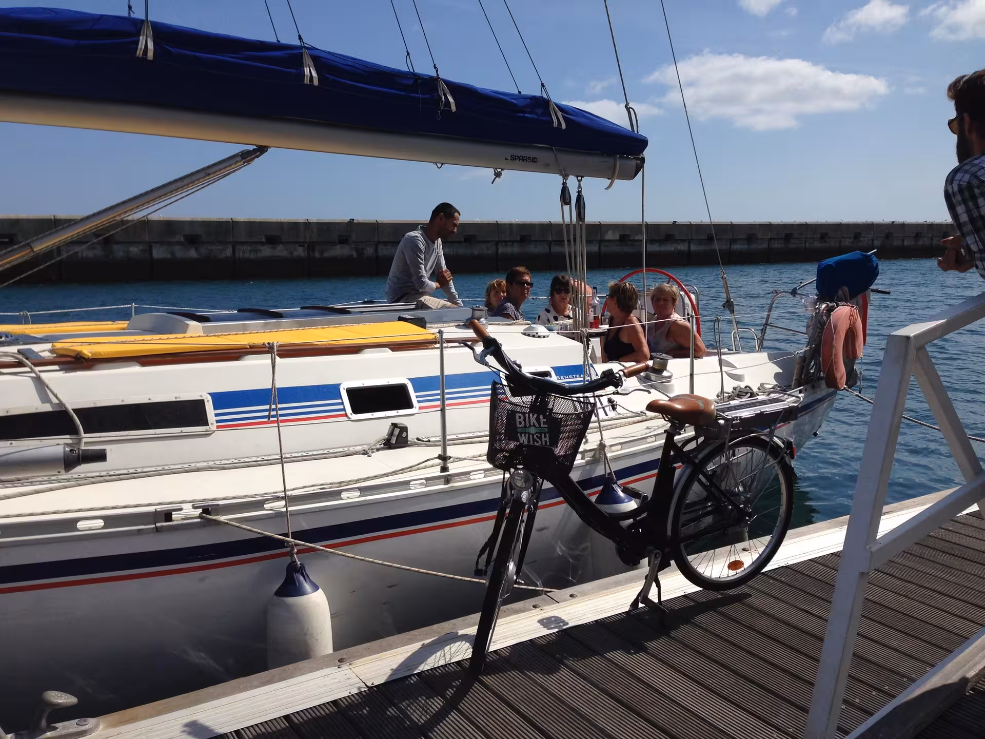Guests aboard sailboat at dock with bicycle ready, combining coastal bike tour and relaxing boat sailing trip