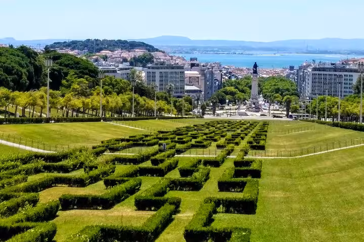 Panoramic view of Lisbon's Eduardo VII Park with lush gardens and a distant cityscape under a clear sky.