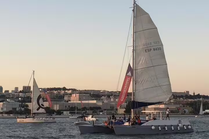 Catamaran sailing near Lisbon's coast during sunset on a private tour, ideal for groups up to 18 people.
