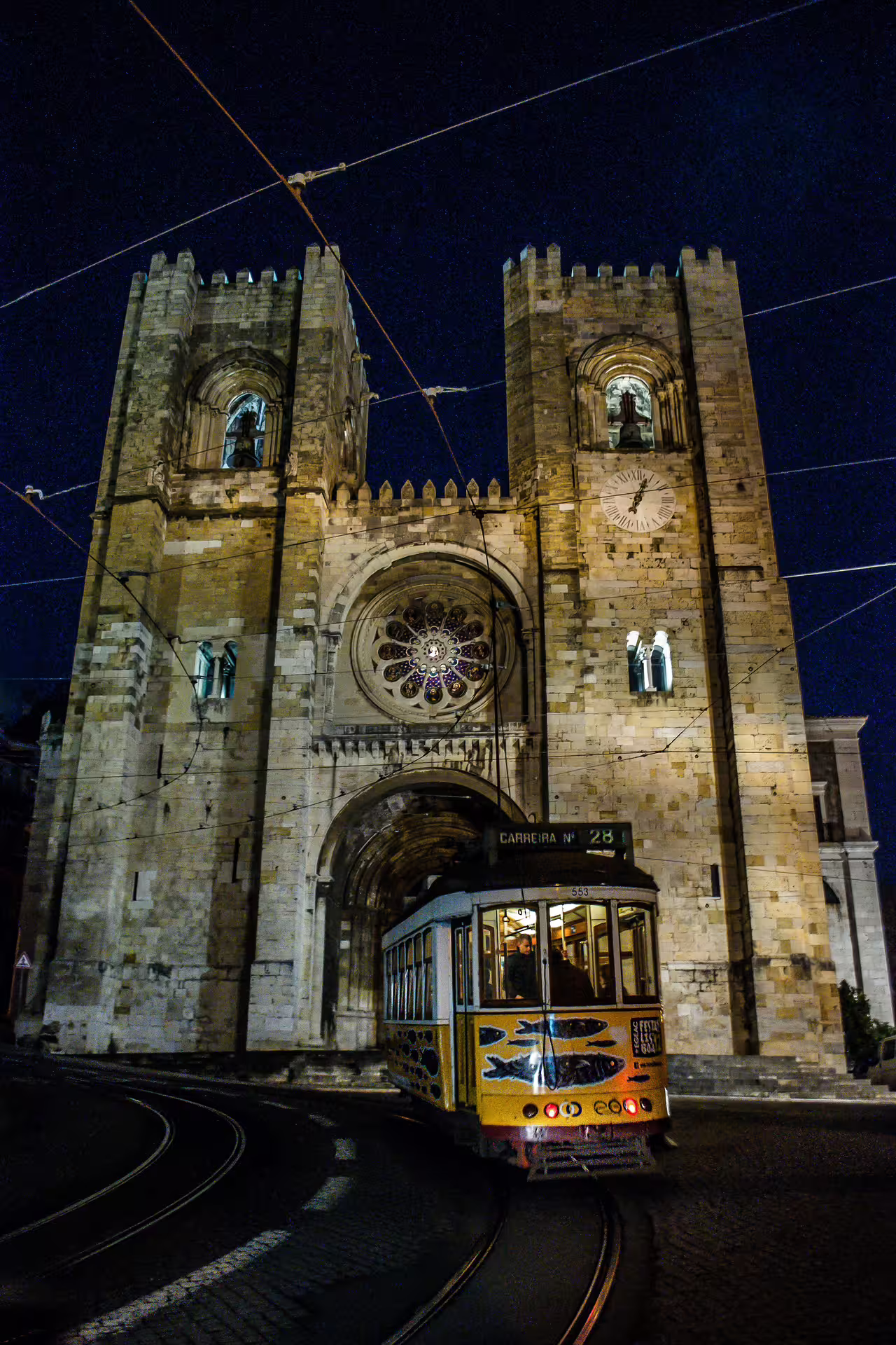 Historic tram passing Lisbon Cathedral at night during a private photo walk, capturing the city's enchanting evening ambiance.
