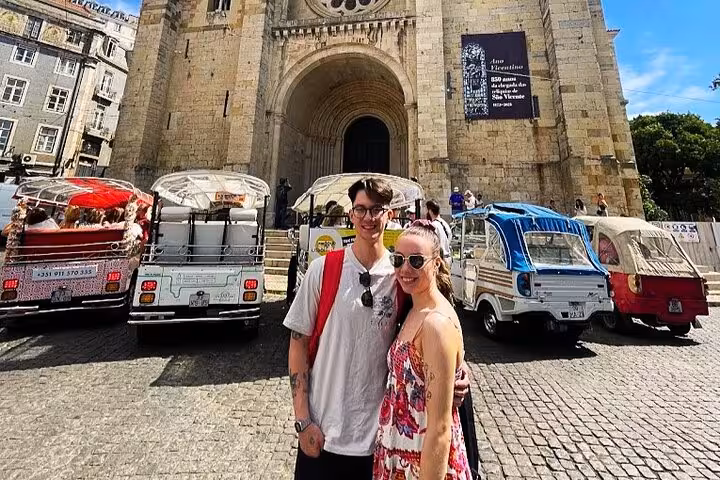 Couple by tuk tuks at Lisbon Cathedral on a 3-hour private tuk tuk tour of Lisbon historic center