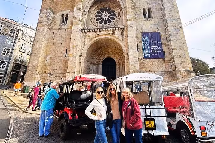 Guests pose by tuk tuk outside Lisbon Cathedral on a 2-hour private historic Lisbon tuk tuk tour
