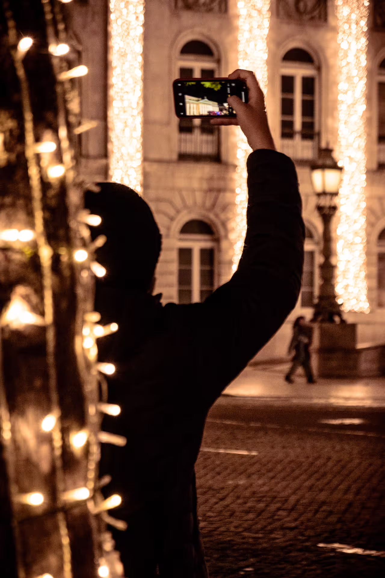 Person capturing Lisbon's festive Christmas lights at night, highlighting illuminated architecture on a private photo walk.