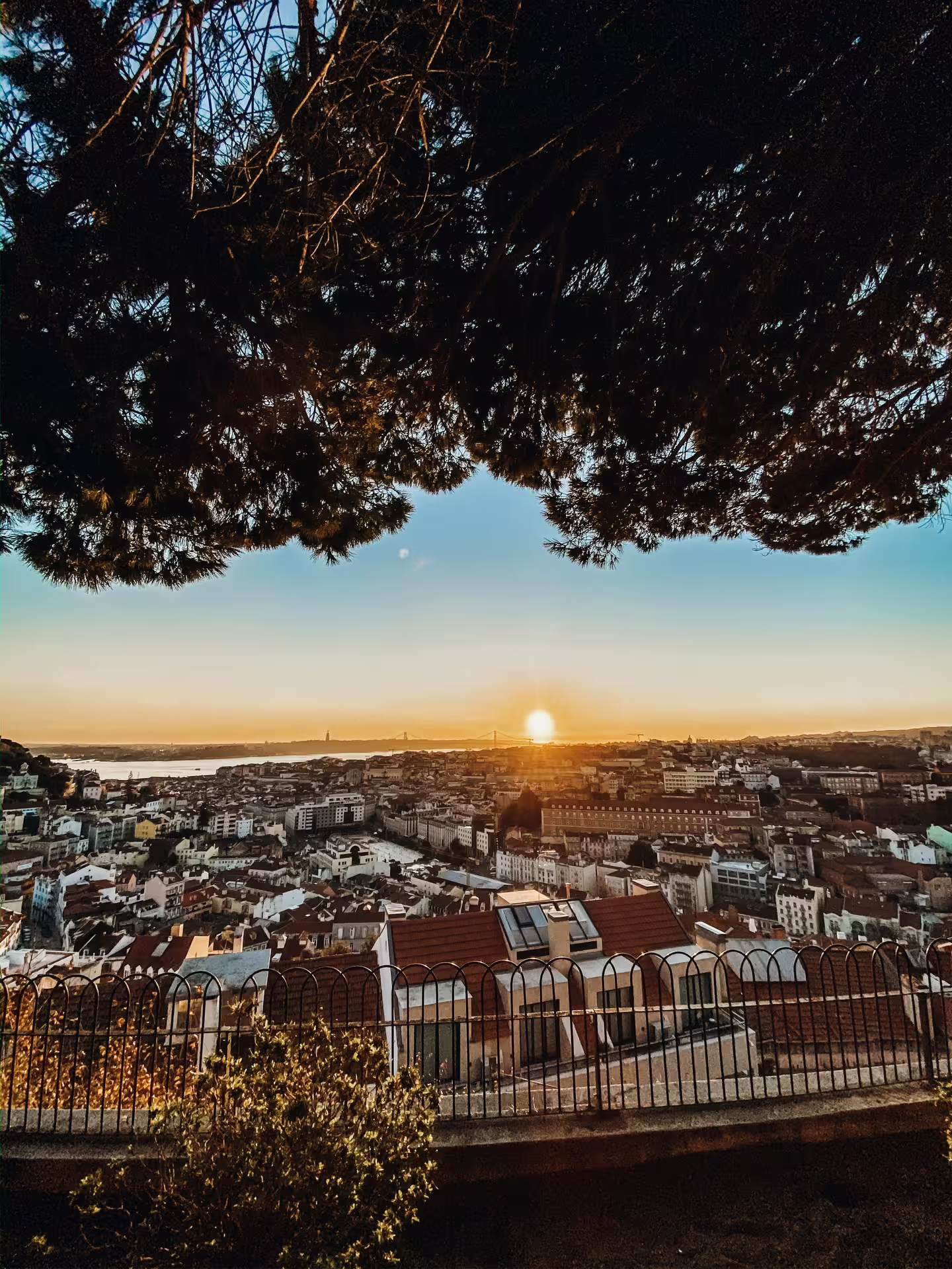 Panoramic view of Lisbon cityscape at sunset from a scenic overlook.
