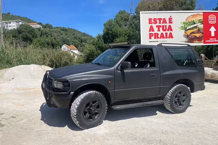 Black 4x4 Jeep parked on a sunny dirt road in Arrábida, Sesimbra-Lisbon, showcasing a scenic adventure tour route.