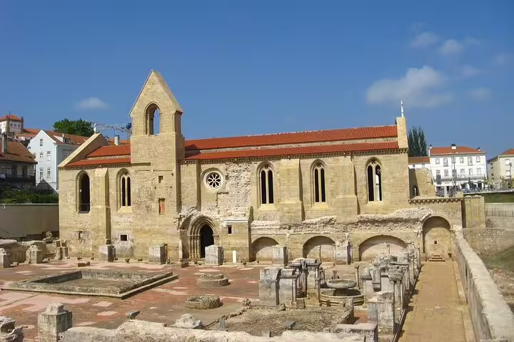 Historic ruins of Santa Clara-a-Velha Monastery in Coimbra under a clear blue sky, featured on the Lisbon to Coimbra private journey.