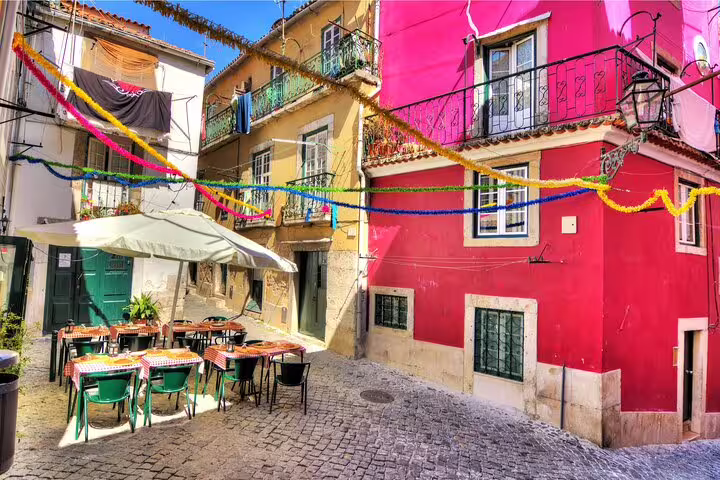 Charming Lisbon alley with colorful buildings and festive decorations, showcasing vibrant culture on a private walking tour.