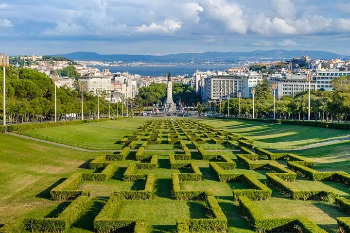 Panoramic view of Eduardo VII Park in Lisbon with geometric hedges, offering a picturesque cityscape and distant river.