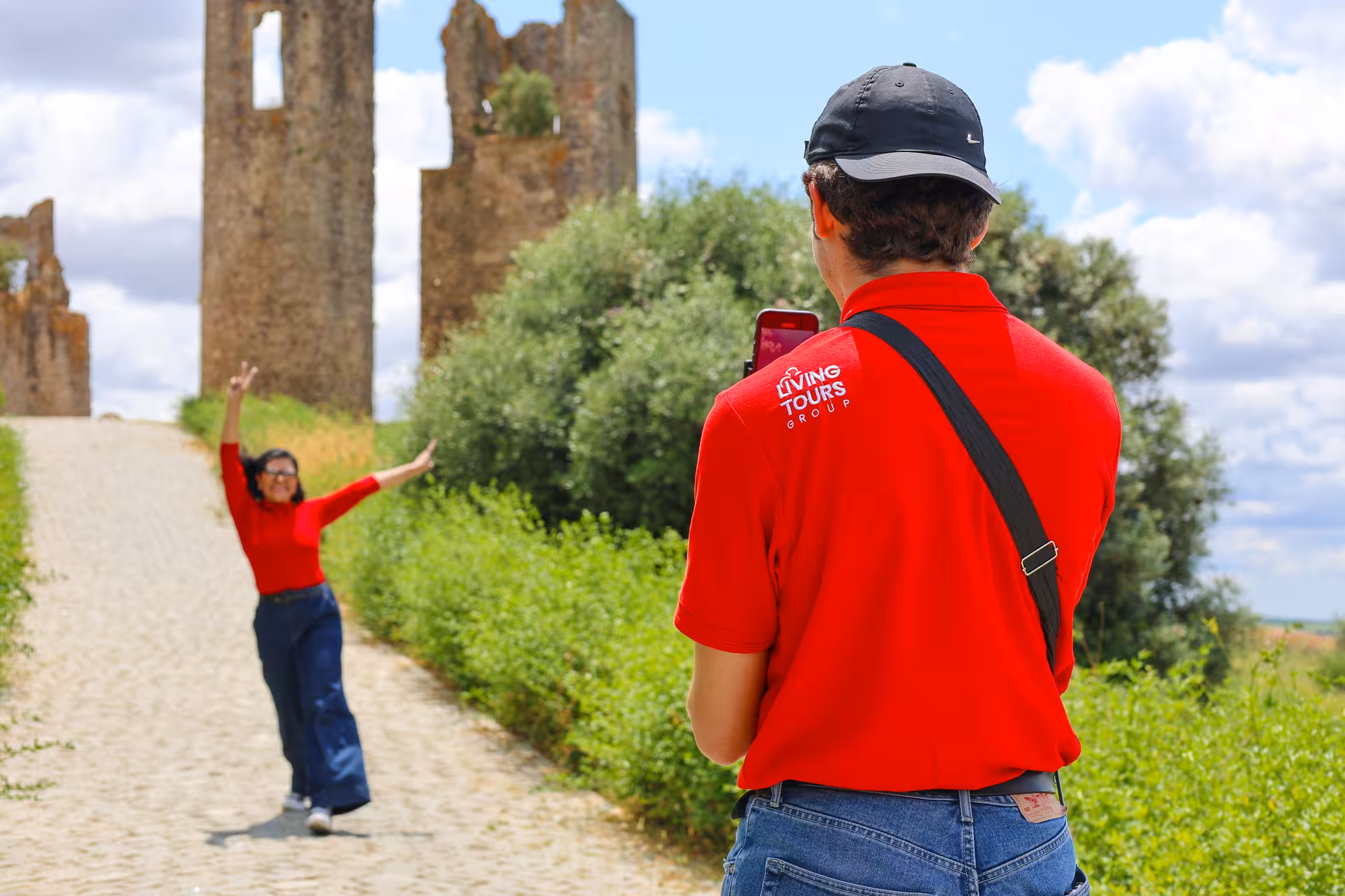 Tour guide photographing a joyful tourist at the ruins of a historic site in Alentejo, Portugal.