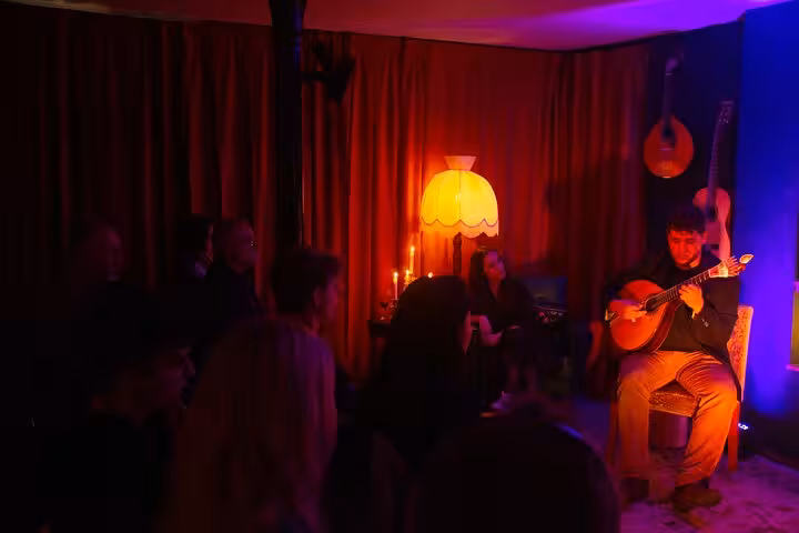Intimate Lisbon Fado concert with guitarist and audience in dimly lit room, creating an authentic cultural experience.
