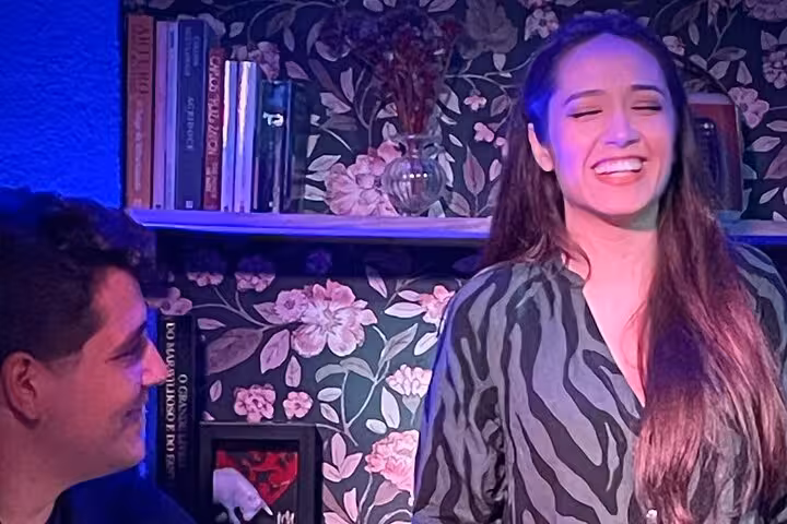 Smiling performer at Lisbon Fado concert, surrounded by floral decor, adding charm to the cultural experience.
