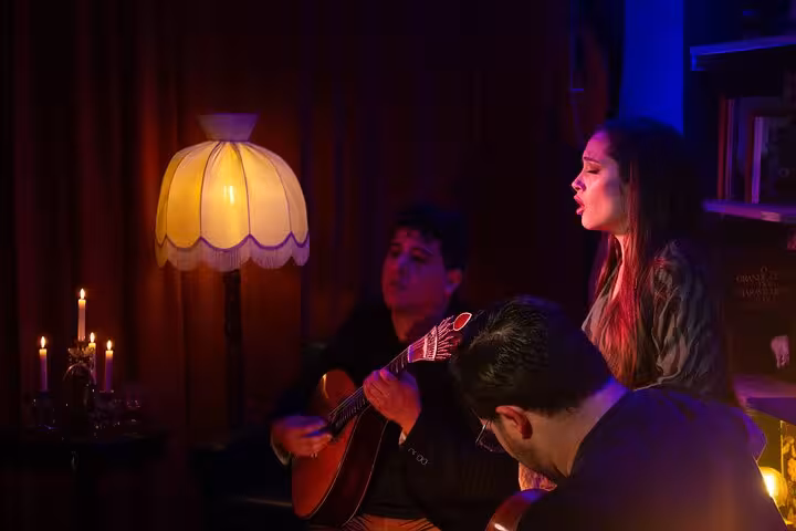 Passionate Fado singer and guitarist performing in cozy Lisbon venue under warm ambient lighting.