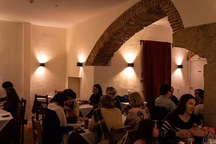 Guests enjoying a vibrant dinner at a Lisbon Fado show, surrounded by rustic decor and lively atmosphere.