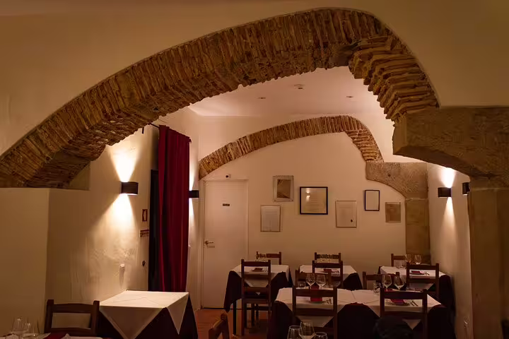 Intimate restaurant setting in Lisbon featuring rustic arches and soft lighting for a Fado dinner performance.