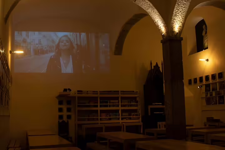 Dimly lit Lisbon venue with projected video, setting the scene for an authentic Portuguese Fado music and dining event.