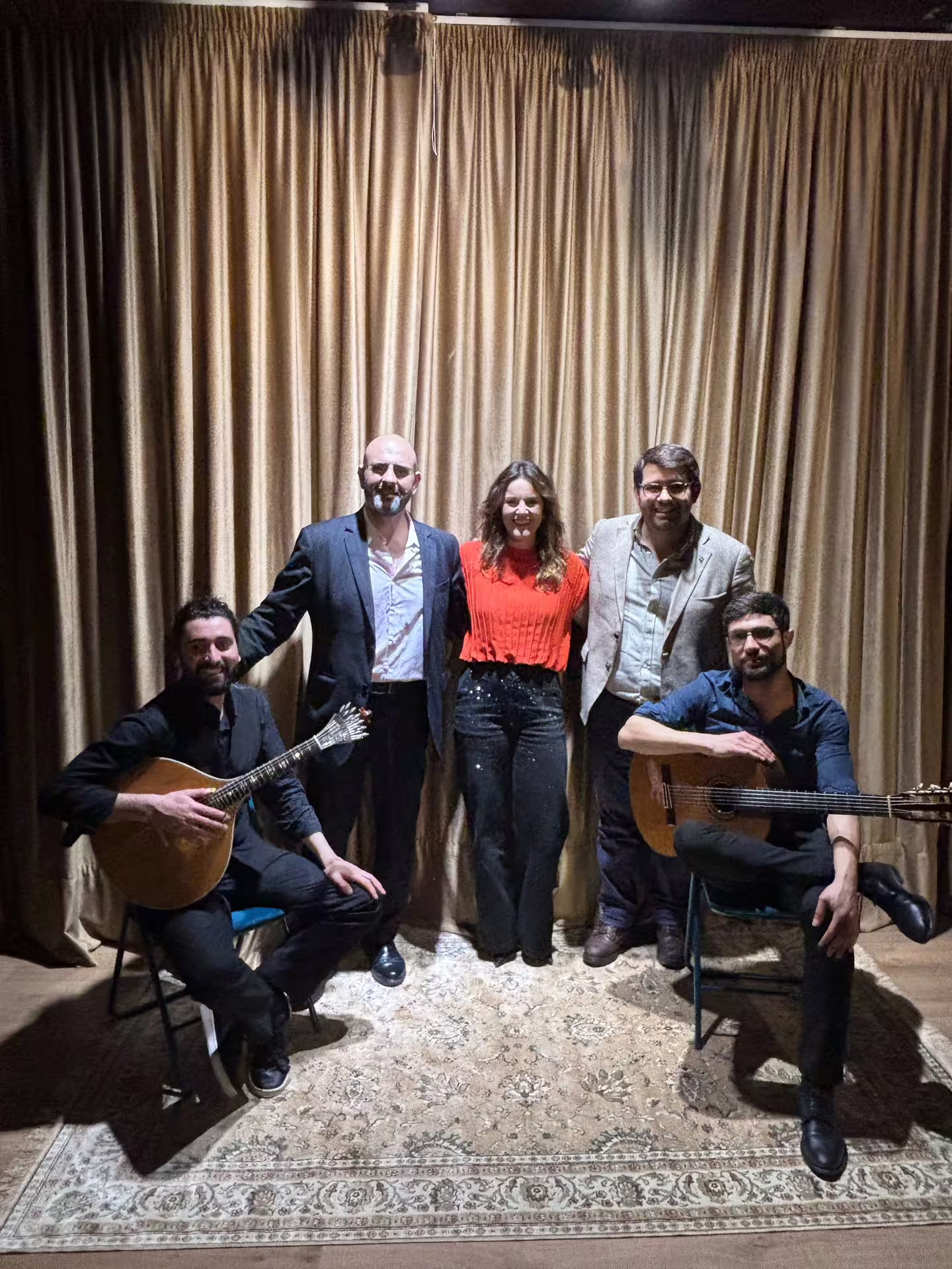 Fado musicians and vocalists pose together on stage, ready to deliver an authentic Portuguese musical experience.