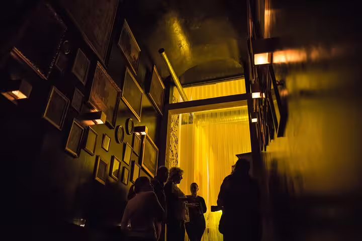 Guests gathering in a dimly lit hallway with framed art, setting the ambiance for a Fado music night in Lisbon.