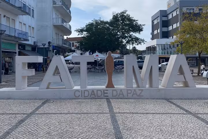Fátima sign in a bustling square, a key stop on the Lisbon to Fátima/Batalha/Nazaré & Óbidos guided tour.