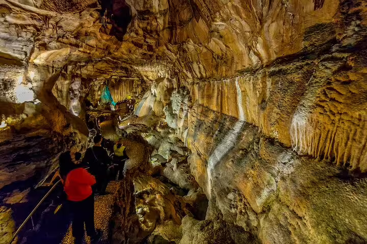 Visitors exploring stunning limestone formations inside a massive cave during a private full-day tour from Lisbon to Fatima.