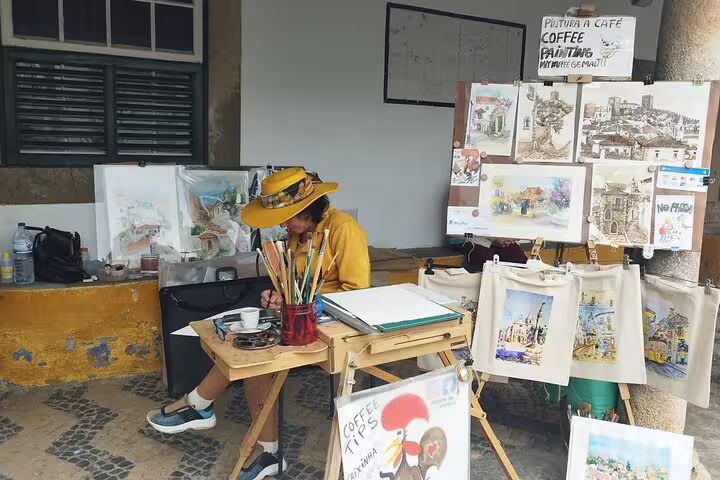 Artist creating coffee paintings in a vibrant street market on a private full-day Fatima Nazare Obidos tour from Lisbon.