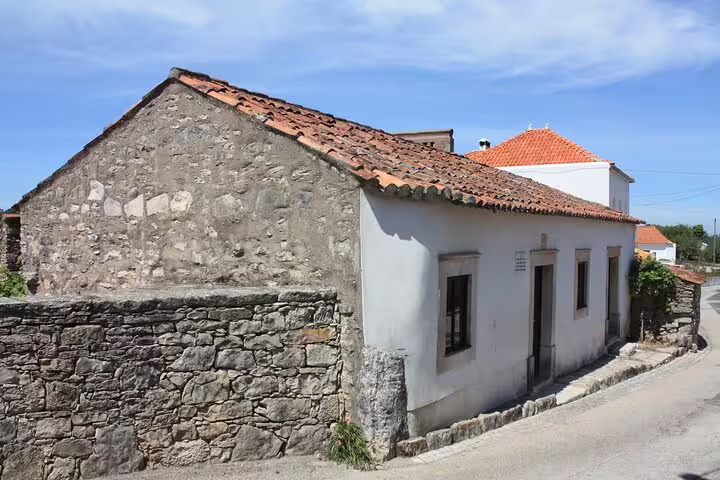 Exterior view of the Little Shepherds' childhood home in Fátima, highlighting its rustic stone and whitewashed walls.
