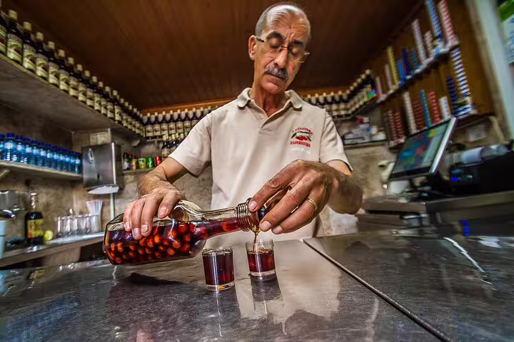 Man pouring traditional Portuguese ginjinha into glasses at a local Lisbon bar, showcasing authentic cultural experiences.