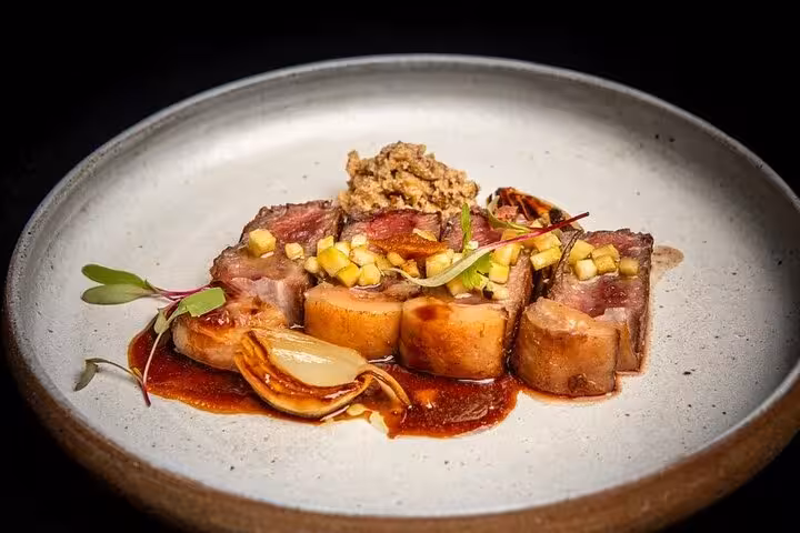 Elegant dish with sliced meat, onions, and sauce on a white plate, showcasing Lisbon's gourmet cuisine.