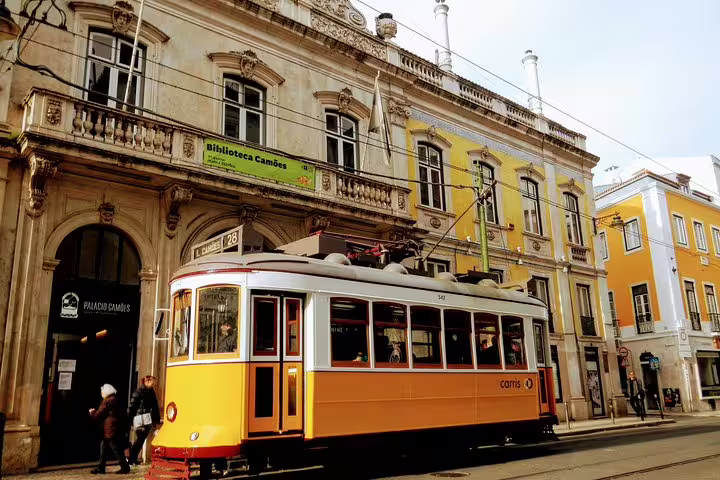 Historic Lisbon tram passing by the ornate Biblioteca Camões building, capturing the charm of Lisbon's World Heritage sites.