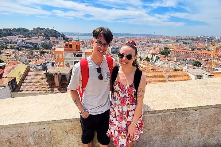 Couple enjoying Miradouro city views on a 3-hour private tuk tuk tour of Lisbon historic center
