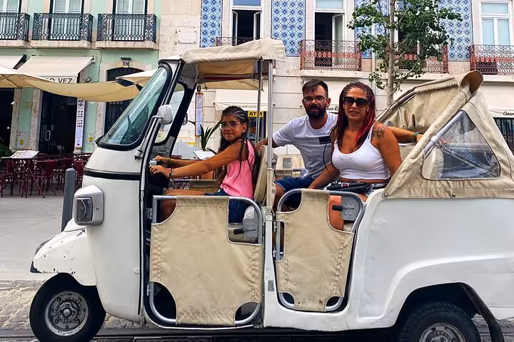 Family riding tuk tuk in Lisbon historic center past azulejo facades on a 3-hour private tour