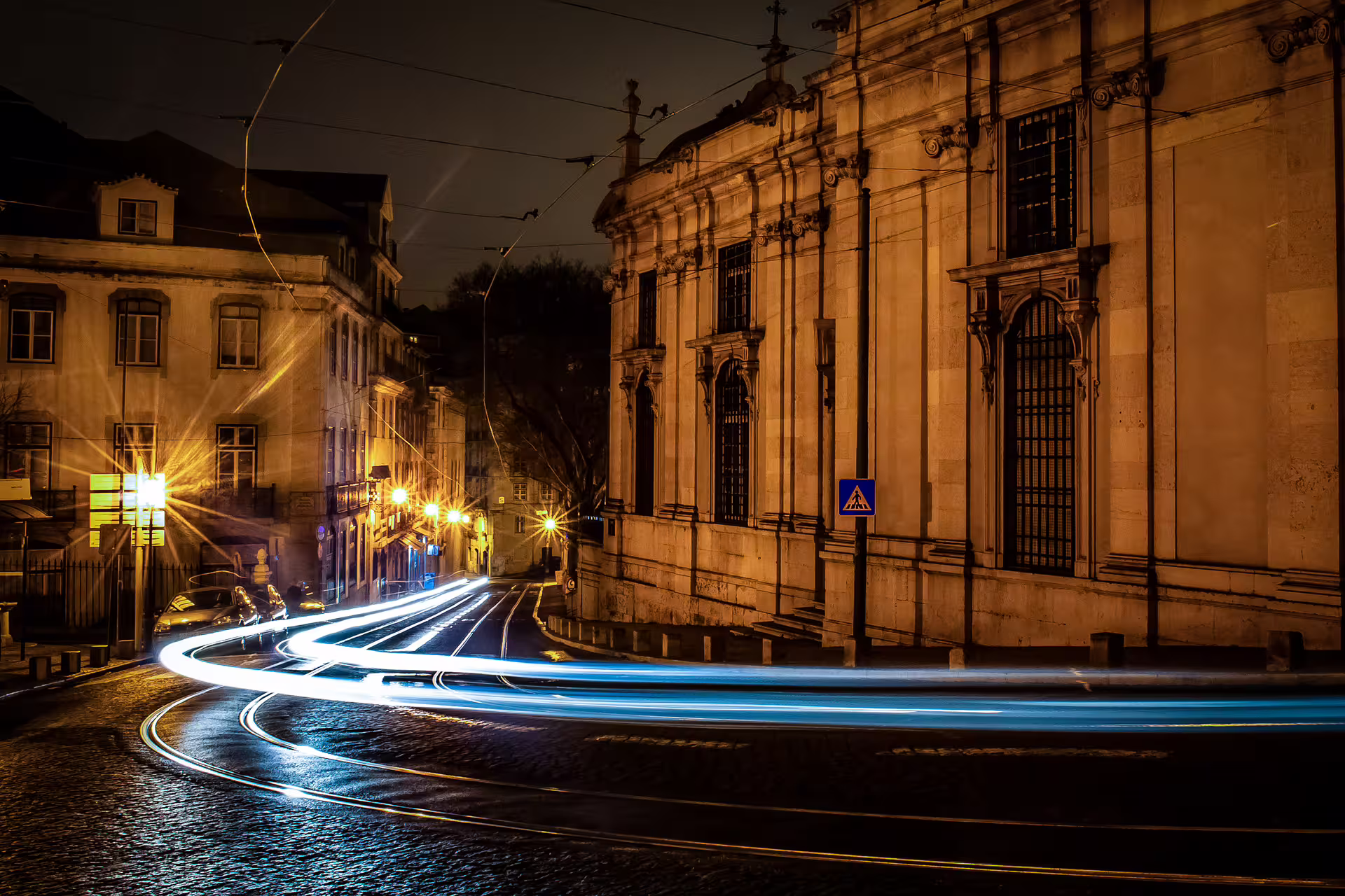 Lisbon's historic streets illuminated at night, showcasing light trails from passing trams during a private sunset photo walk.