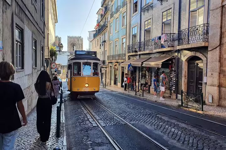 Historic tram navigating the charming streets of Lisbon's Old Town during a small-group full-day tour, with vibrant architecture.