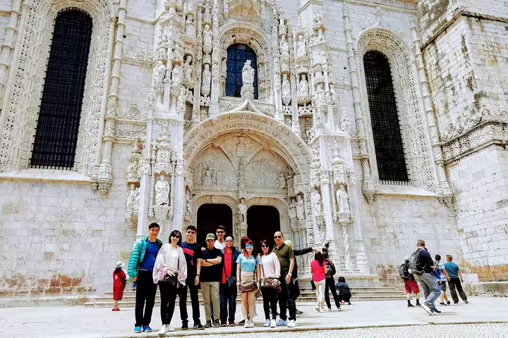A group of tourists explores the stunning Gothic architecture of Jerónimos Monastery on the Lisbon World Heritage Deluxe Tour.