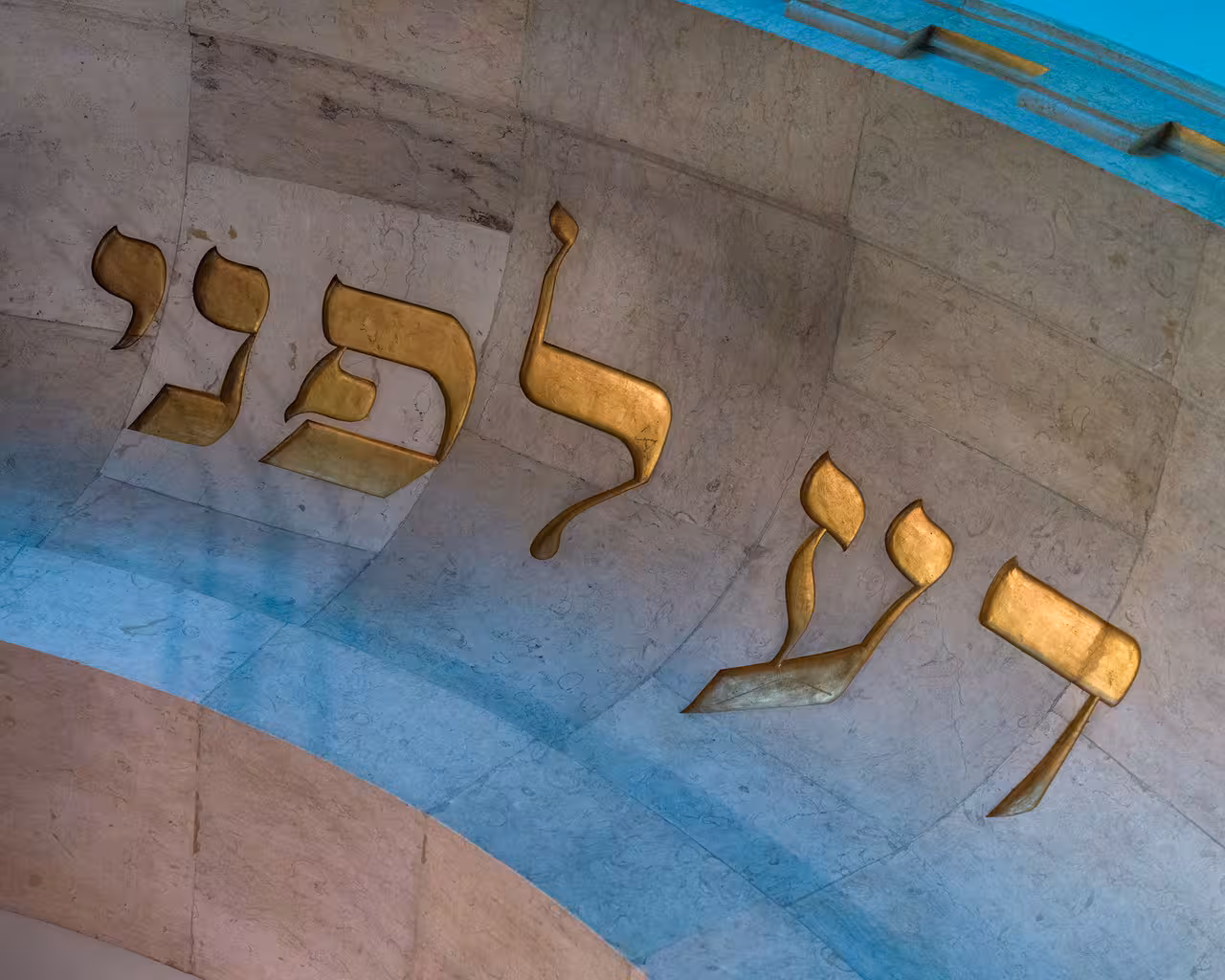 Golden Hebrew letters on a stone archway in Lisbon, highlighting the city's rich Jewish heritage.