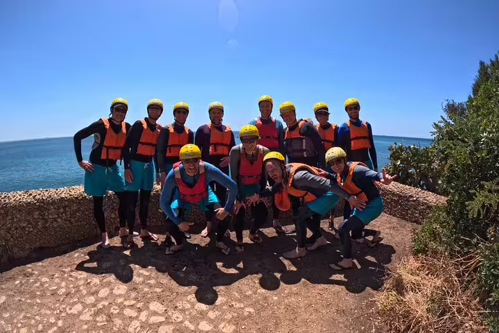 Group ready for Lisbon kayak and snorkeling adventure, wearing safety gear on a sunny coastal day with ocean views.
