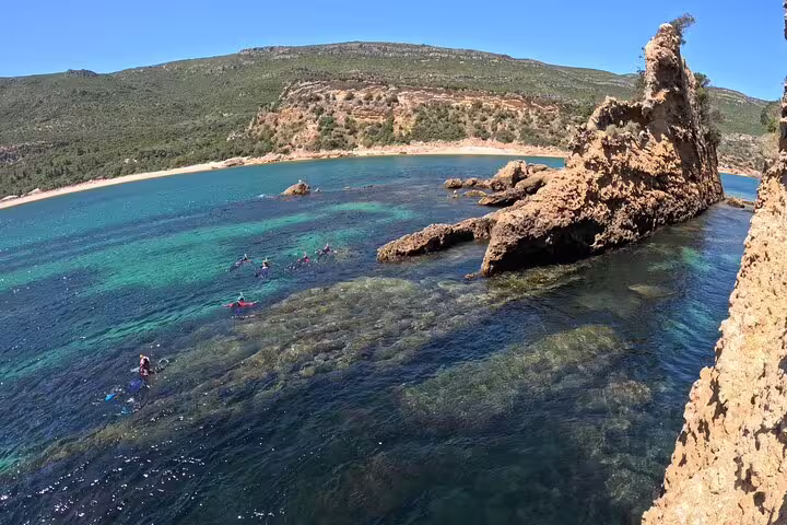 Kayakers explore clear blue waters and rugged coastline during Lisbon's full-day coasteering adventure.