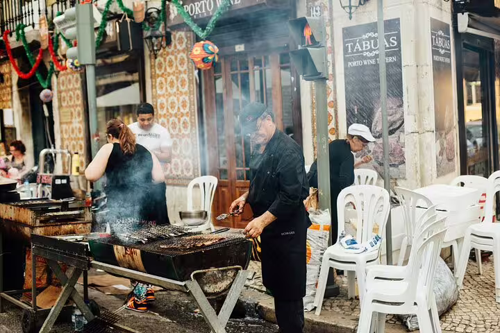 Local chef grills food on a bustling Lisbon street, showcasing authentic Portuguese flavors on a private city tour.
