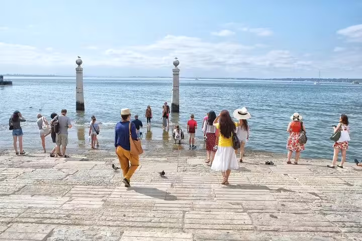 People enjoying the serene riverside view at Cais das Colunas, Lisbon on a sunny day, perfect for a local private tour experience.