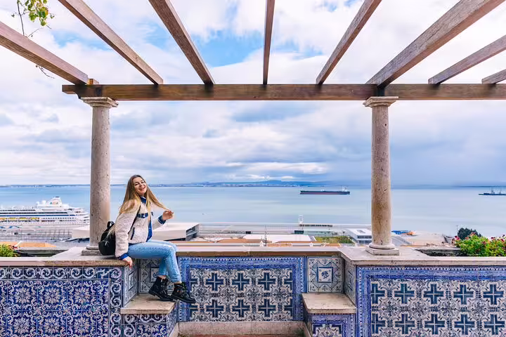 Woman enjoying panoramic ocean view from a tiled terrace in Lisbon, capturing the essence of a local tour off the tourist path.