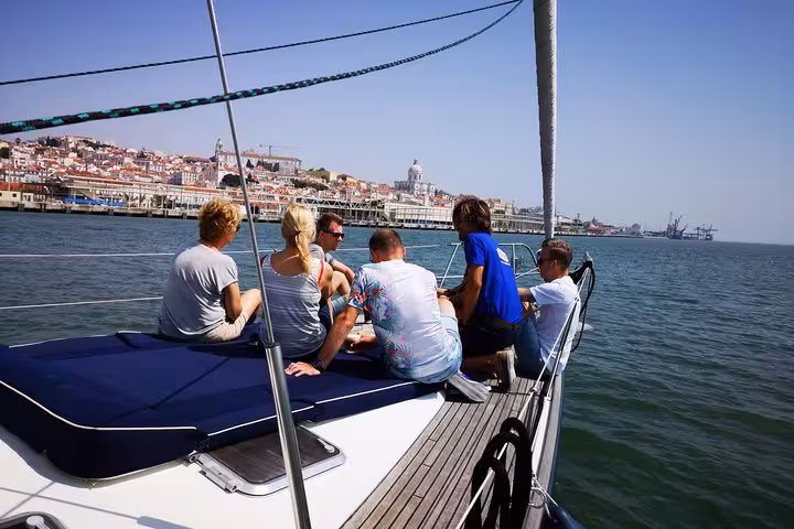 Guests relaxing on luxury sailing yacht deck on Tagus River, Lisbon sailing tour with 2 drinks and city views