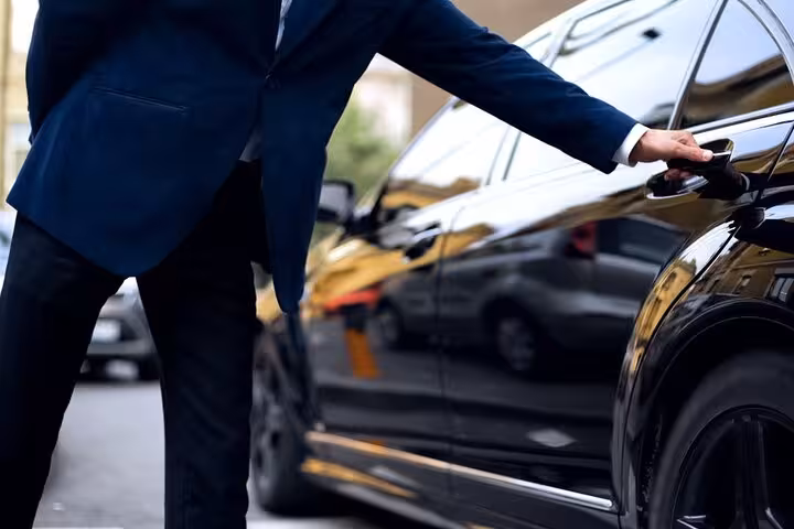 Chauffeur opening door of luxury Mercedes for Lisbon to Madrid private transfer service.