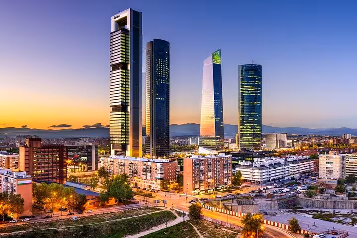 Madrid's modern skyline featuring the Four Towers at sunset, an iconic sight on the Lisbon to Madrid private Mercedes transfer.