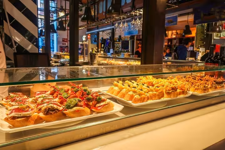 Gourmet tapas displayed in a bustling Madrid market, a culinary highlight on the Lisbon to Madrid private transfer tour.